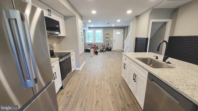 248 W Edgevale Rd, Baltimore, MD 21225 - kitchen featuring stainless steel appliances, a sink, light wood finished floors, white cabinets, and light stone counters
