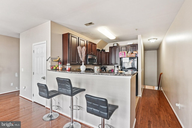 361 Union St, Trenton, NJ 08611 - kitchen with stainless steel microwave, light wood-style floors, dark brown cabinets, a peninsula, and a kitchen breakfast bar