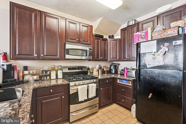 361 Union St, Trenton, NJ 08611 - kitchen featuring appliances with stainless steel finishes, light tile patterned flooring, dark brown cabinetry, dark stone counters, and vaulted ceiling