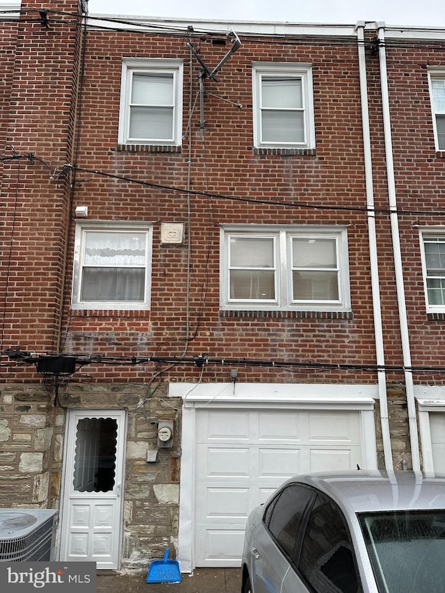 4304 Oakmont St, Philadelphia, PA 19136 - view of front facade with brick siding, stone siding, cooling unit, and an attached garage