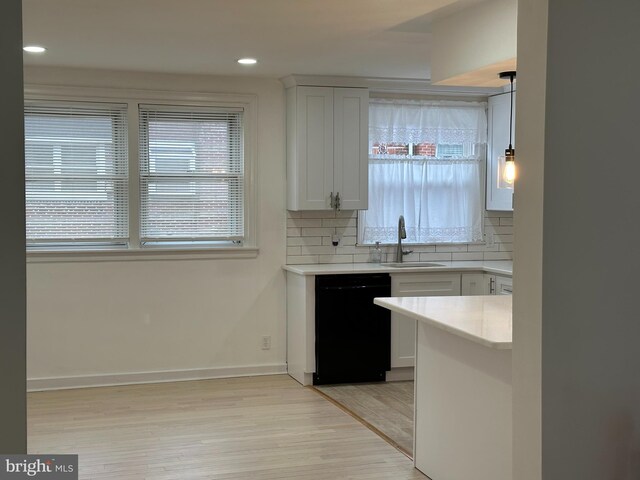 4304 Oakmont St, Philadelphia, PA 19136 - kitchen with black dishwasher, a sink, light wood-style flooring, decorative backsplash, and light countertops
