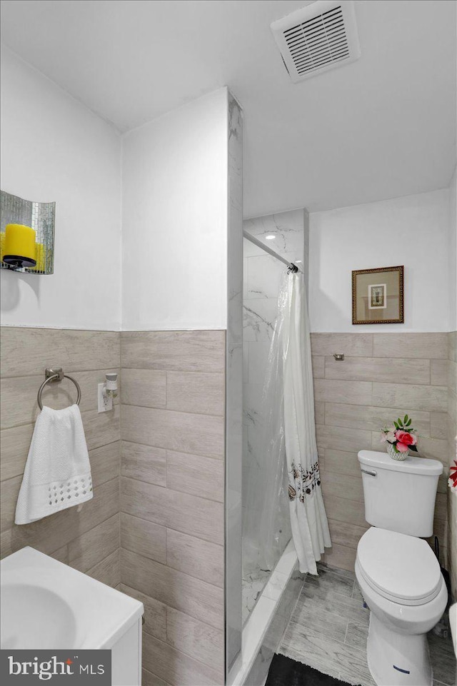 542 S 12th St, Reading, PA 19602 - full bathroom with tile walls, a stall shower, toilet, vanity, and a wainscoted wall
