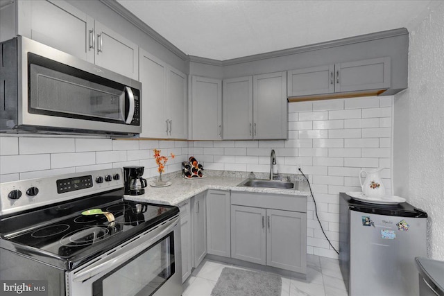 542 S 12th St, Reading, PA 19602 - kitchen with appliances with stainless steel finishes, gray cabinets, a sink, tasteful backsplash, and ornamental molding