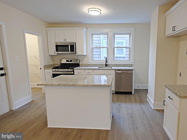 22 Leeway Rd, Baltimore, MD 21222 - kitchen featuring appliances with stainless steel finishes, light wood-style flooring, a sink, white cabinetry, and a kitchen island