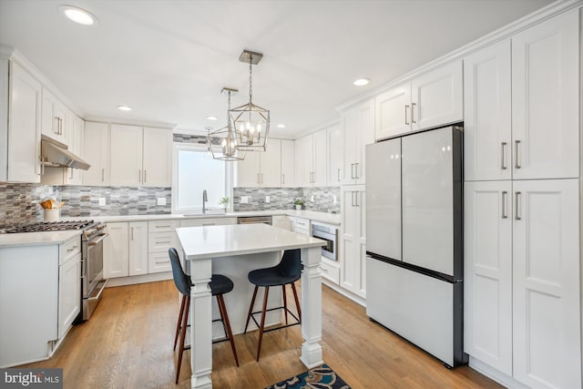2709 Emmet Rd, Silver Spring, MD 20902 - kitchen with stainless steel appliances, a sink, under cabinet range hood, decorative backsplash, and recessed lighting