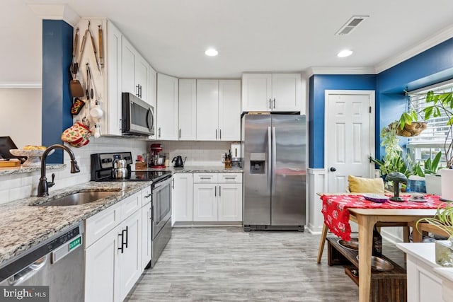 71 Sudbury Sq, Sterling, VA 20164 - kitchen with stainless steel appliances, a sink, white cabinets, light stone countertops, and ornamental molding