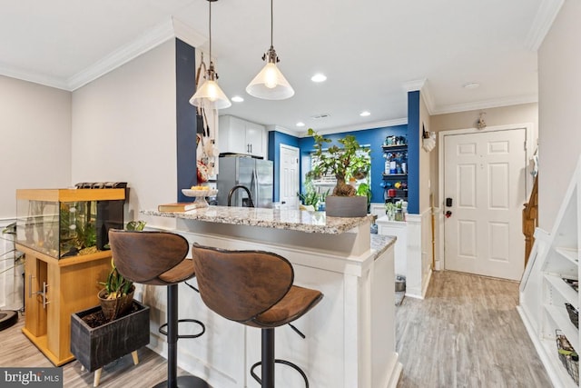 71 Sudbury Sq, Sterling, VA 20164 - kitchen with freestanding refrigerator, crown molding, light wood-style flooring, a kitchen bar, and pendant lighting
