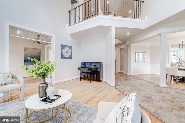42720 Mount Auburn Pl, Broadlands, VA 20148 - living area featuring a towering ceiling, ornamental molding, a decorative wall, and wood finished floors