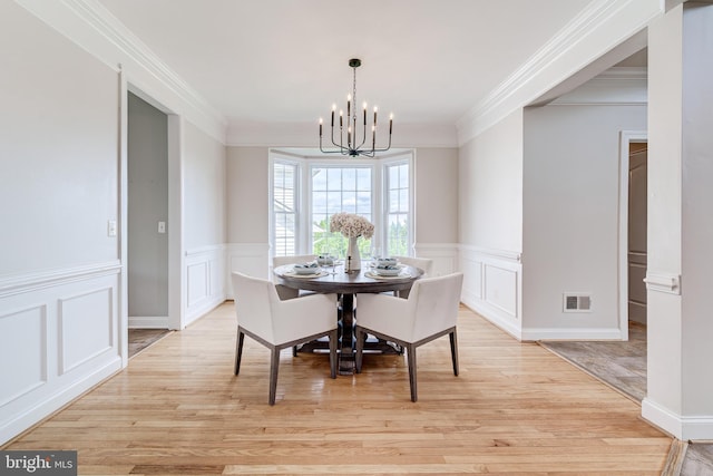42720 Mount Auburn Pl, Broadlands, VA 20148 - dining space featuring a chandelier, ornamental molding, a decorative wall, light wood finished floors, and a wainscoted wall