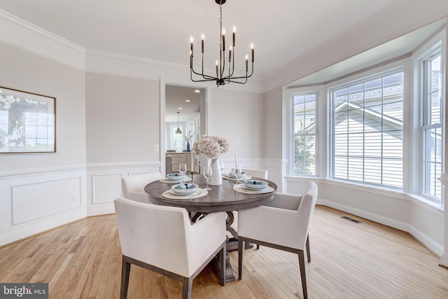 42720 Mount Auburn Pl, Broadlands, VA 20148 - dining room featuring a chandelier, ornamental molding, light wood-type flooring, a wainscoted wall, and a decorative wall