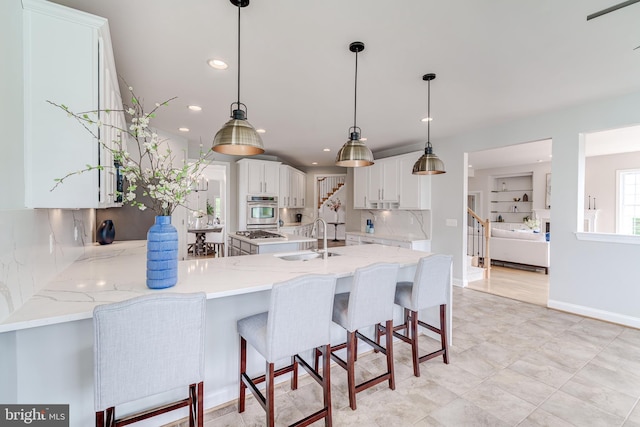 42720 Mount Auburn Pl, Broadlands, VA 20148 - kitchen featuring stainless steel oven, a sink, a peninsula, white cabinets, and light stone counters