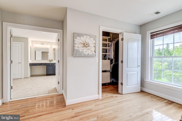 42720 Mount Auburn Pl, Broadlands, VA 20148 - unfurnished bedroom featuring a walk in closet, baseboards, multiple windows, and light wood-style flooring