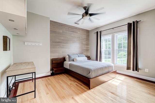 42720 Mount Auburn Pl, Broadlands, VA 20148 - bedroom with an accent wall, baseboards, light wood finished floors, ceiling fan, and wood walls
