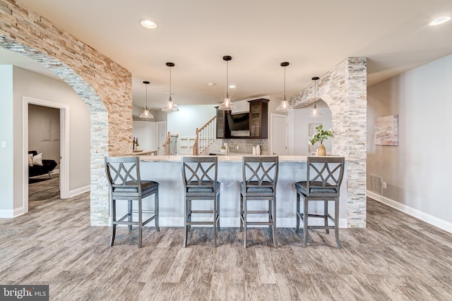 42720 Mount Auburn Pl, Broadlands, VA 20148 - kitchen featuring a breakfast bar area, light countertops, wood finished floors, arched walkways, and recessed lighting