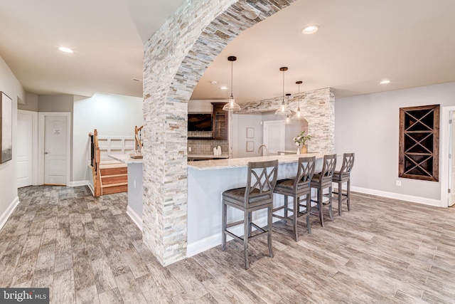 42720 Mount Auburn Pl, Broadlands, VA 20148 - kitchen with wood finished floors, a breakfast bar area, hanging light fixtures, a peninsula, and recessed lighting