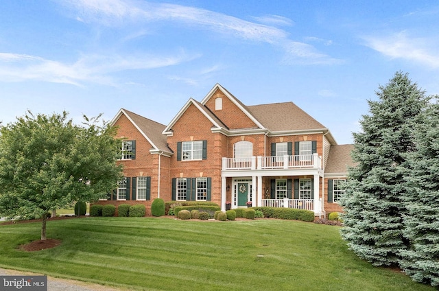 22415 Conservancy Dr, Ashburn, VA 20148 - colonial house featuring a balcony, brick siding, a front lawn, and covered porch