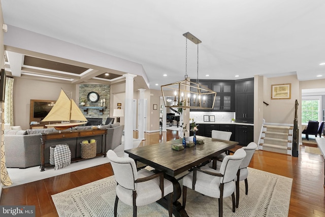 22415 Conservancy Dr, Ashburn, VA 20148 - dining space featuring a chandelier, wood finished floors, stairway, decorative columns, and recessed lighting