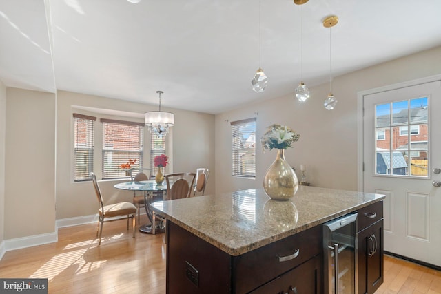 1317 Winston Ave, Baltimore, MD 21239 - kitchen featuring beverage cooler, light wood-type flooring, dark brown cabinets, a center island, and decorative light fixtures