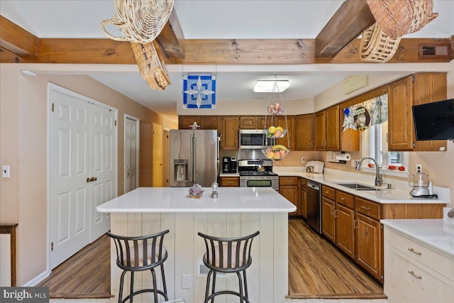 15 Hamilton Ct, Lawrenceville, NJ 08648 - kitchen featuring appliances with stainless steel finishes, a sink, wood finished floors, brown cabinetry, and a center island