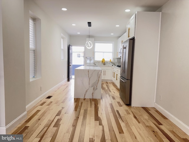 2015 S 23rd St, Philadelphia, PA 19145 - kitchen with high end fridge, a kitchen island, light wood-style flooring, white cabinetry, and hanging light fixtures