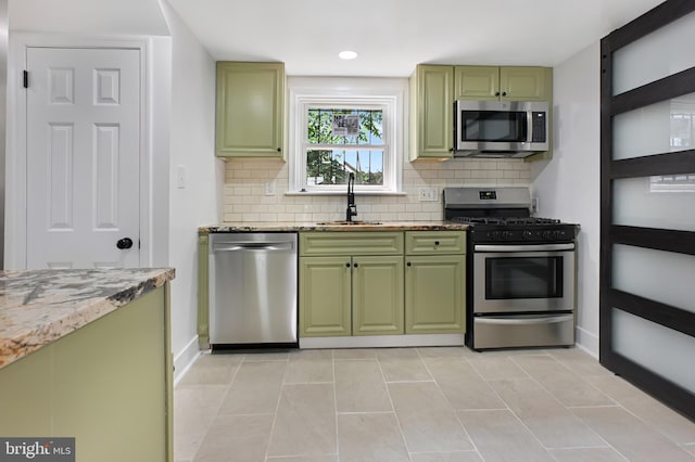 4504 Clay St NE, Washington, DC 20019 - kitchen featuring stainless steel appliances, green cabinets, a sink, backsplash, and baseboards