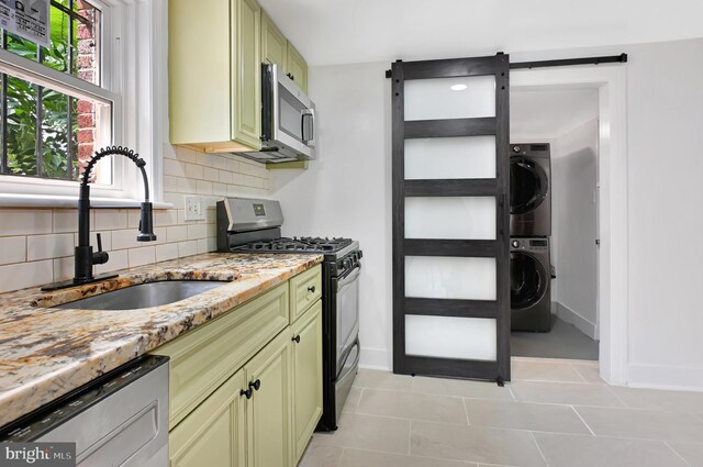 4504 Clay St NE, Washington, DC 20019 - kitchen featuring appliances with stainless steel finishes, a sink, green cabinets, and stacked washer / drying machine