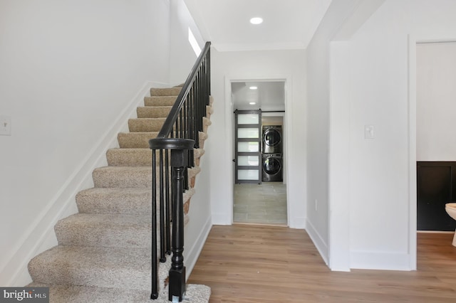 4504 Clay St NE, Washington, DC 20019 - staircase with stacked washer and clothes dryer, wood finished floors, baseboards, crown molding, and a barn door