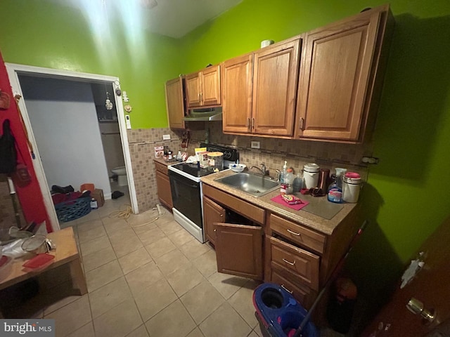 2844 N Hancock St, Philadelphia, PA 19133 - kitchen featuring range with electric stovetop, under cabinet range hood, light tile patterned flooring, a sink, and light countertops