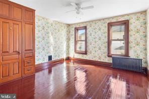 401 Fulton St, Hanover, PA 17331 - empty room featuring radiator, wood finished floors, wallpapered walls, a ceiling fan, and baseboards