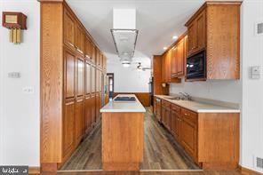 401 Fulton St, Hanover, PA 17331 - kitchen with black microwave, brown cabinetry, light countertops, and wood finished floors