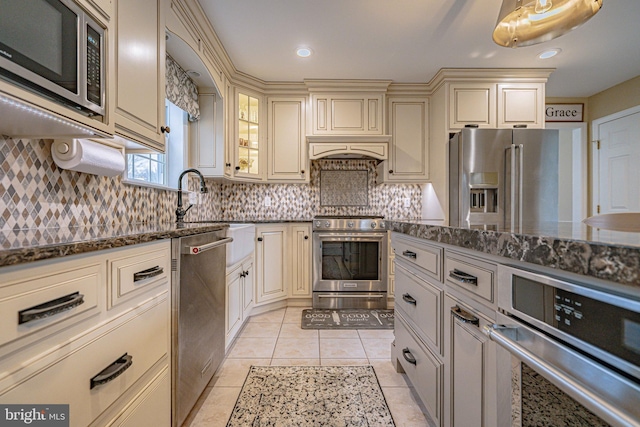 4408 Irish Creek Rd, Bernville, PA 19506 - kitchen with cream cabinetry, appliances with stainless steel finishes, dark stone countertops, tasteful backsplash, and light tile patterned flooring