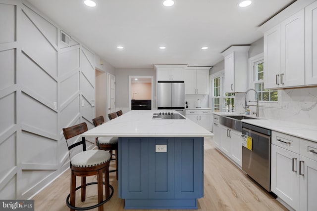 10401 Zion Dr, Fairfax, VA 22032 - kitchen with appliances with stainless steel finishes, a sink, a kitchen bar, light wood finished floors, and recessed lighting