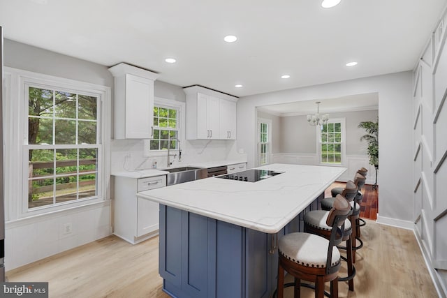 10401 Zion Dr, Fairfax, VA 22032 - kitchen featuring a sink, a kitchen island, white cabinetry, black electric cooktop, and light wood-style flooring