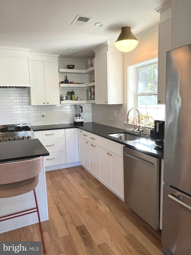 3200 Winnett Rd, Chevy Chase, MD 20815 - kitchen featuring appliances with stainless steel finishes, a sink, open shelves, dark countertops, and light wood-style flooring