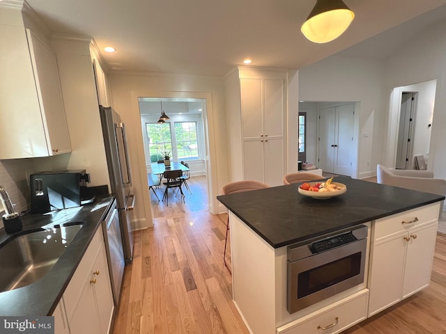 3200 Winnett Rd, Chevy Chase, MD 20815 - kitchen featuring dark countertops, appliances with stainless steel finishes, light wood finished floors, white cabinets, and recessed lighting