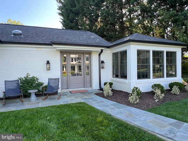 3200 Winnett Rd, Chevy Chase, MD 20815 - doorway to property featuring brick siding, a yard, and a shingled roof