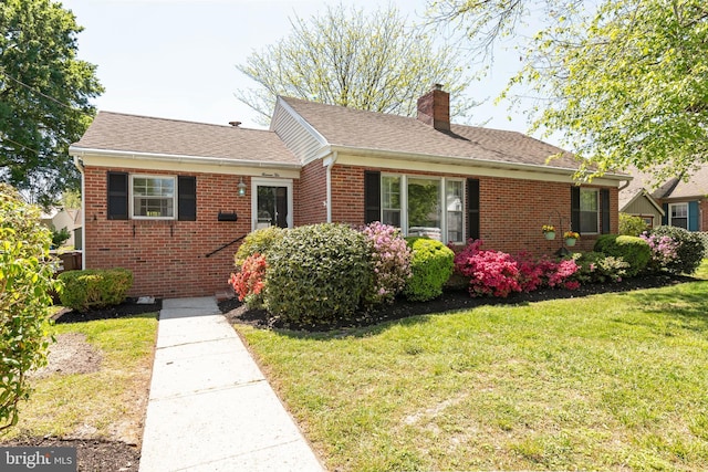 1110 Holland Ave, Cambridge, MD 21613 - view of front of house featuring a chimney, a front yard, brick siding, and a shingled roof
