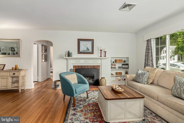 1110 Holland Ave, Cambridge, MD 21613 - living area with arched walkways, wood finished floors, a fireplace, and a baseboard radiator