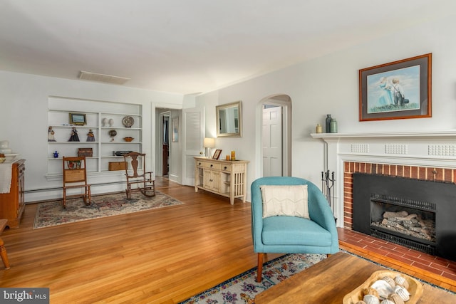 1110 Holland Ave, Cambridge, MD 21613 - living area featuring arched walkways, built in features, a brick fireplace, and wood finished floors