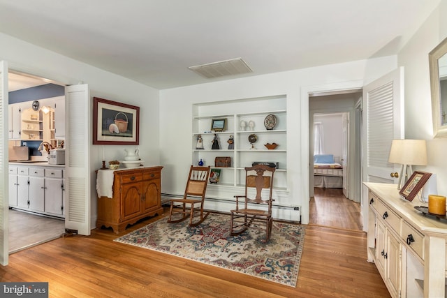1110 Holland Ave, Cambridge, MD 21613 - living area with light wood finished floors, a baseboard heating unit, and built in shelves