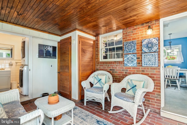 1110 Holland Ave, Cambridge, MD 21613 - living area with stacked washer / drying machine, brick flooring, and wooden ceiling