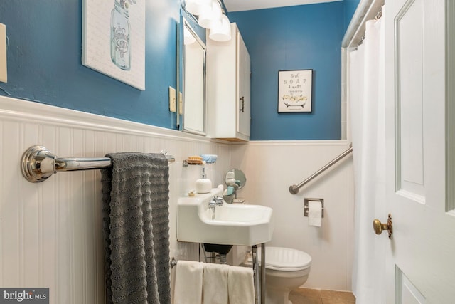 1110 Holland Ave, Cambridge, MD 21613 - bathroom with wainscoting, toilet, tile patterned floors, and a sink
