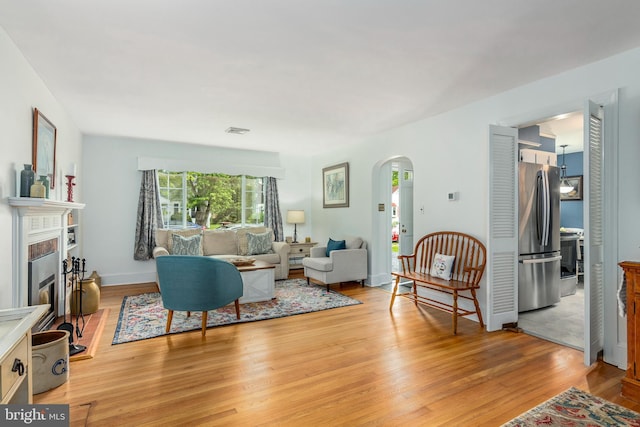 1110 Holland Ave, Cambridge, MD 21613 - living room featuring arched walkways, light wood finished floors, and a fireplace