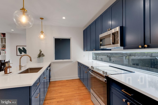 407 Salmon St, Philadelphia, PA 19125 - kitchen with stainless steel appliances, a sink, a peninsula, blue cabinets, and recessed lighting