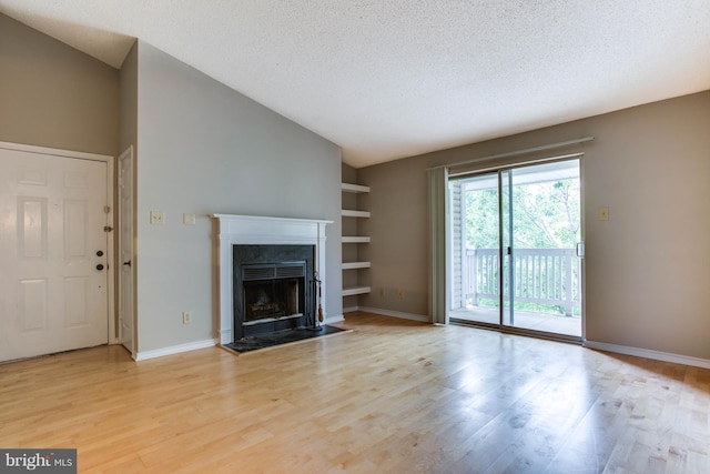 1525 Lincoln Way Unit 301A, Mclean, VA 22102 - unfurnished living room with lofted ceiling, a fireplace, light wood-style flooring, built in shelves, and a textured ceiling