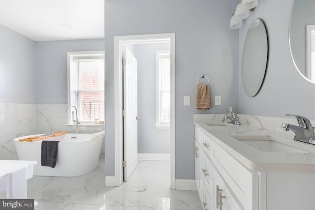 5E 27th St, Baltimore, MD 21218 - full bathroom featuring double vanity, a soaking tub, marble finish flooring, tile walls, and baseboards