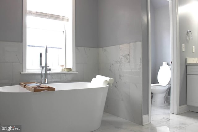 5E 27th St, Baltimore, MD 21218 - full bathroom featuring toilet, a freestanding bath, tile walls, vanity, and marble finish flooring