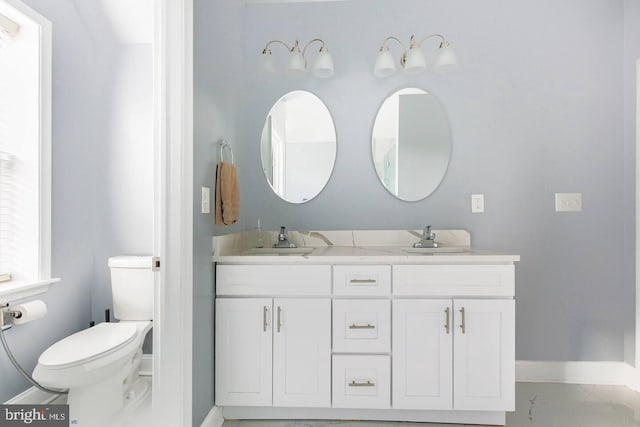 5E 27th St, Baltimore, MD 21218 - bathroom featuring baseboards, double vanity, and toilet