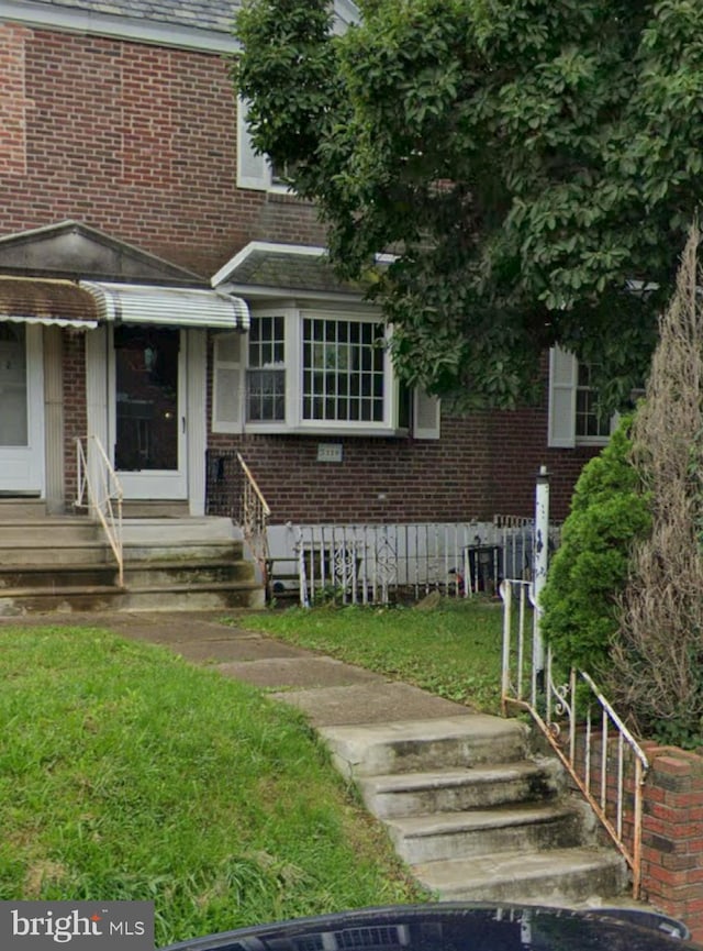 7119 Walker St, Philadelphia, PA 19135 - view of front facade with brick siding, entry steps, and a front lawn