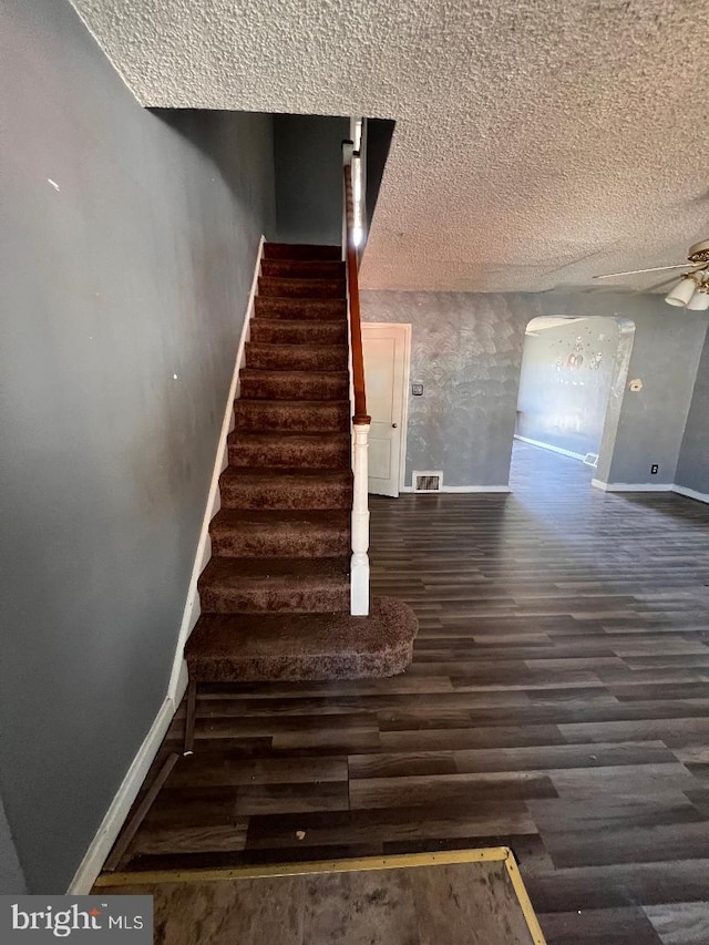 7119 Walker St, Philadelphia, PA 19135 - stairs featuring baseboards, wood finished floors, a textured ceiling, arched walkways, and ceiling fan